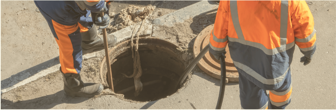 Two workers looking over manhole