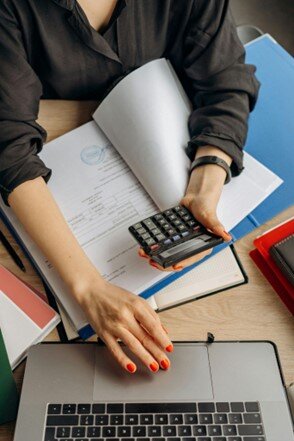 Woman calculating costs with a construction invoice template on laptop