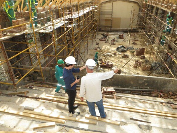 Construction project estimator discussing plans on a busy construction site