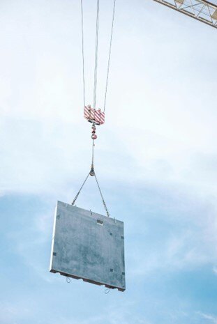 Crane lifting a precast concrete slab, showcasing economical materials for reducing construction costs