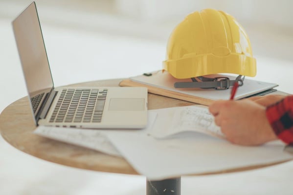 Construction worker writing out rates with laptop open